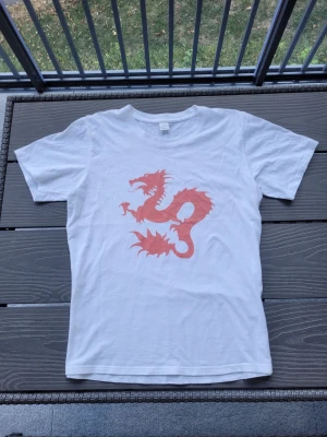 Vit t-shirt med dean blunt motiv - Snygg vit t-shirt med ett dean blunt "zushi" motiv på framsidan. Klassisk passform och rund halsringning. Perfekt för dig som vill sticka ut med en cool print. Tillverkad i mjuk bomull för skön känsla hela dagen.