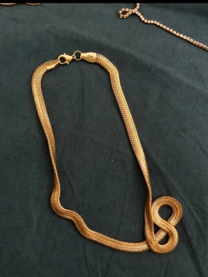Guldigt ormkedjehalsband 24K - Snyggt ormkedjehalsband i guldton med 24K-stämpel. Halsbandet har en platt, glänsande design som ger en modern och stilren look. Perfekt för att lyfta vilken outfit som helst med en touch av lyx.