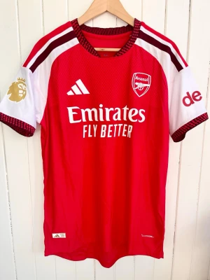 William Saliba - Arsenal 2026/2027 - Player version - Arsenals matchtröja för årets säsong 2026/27 med Saliba på ryggen. Tröjan är en reprint i nyskick med emblem och patchar av högsta kvalité.   Storlek:XL, men liknar mer L/XL. Denna tröja är en player version, tröjan som spelarna själva använder. Bättre kvalité och passform (slim fit).  Kan skickas snabbt eller hämtas i Majorna i Göteborg.    #fifa #WorldCup #panini #fotboll #fifa #Argentina #panini #fotboll #fashion #Messi #Barcelona #Ronaldo