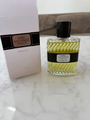 Eau Sauvage Parfum från Dior - Eau Sauvage Parfum från Dior i en elegant glasflaska med räfflat mönster och svart etikett. Parfymen har en gulaktig ton och flaskan har ett svart lock. Medföljer gör originalkartong i vitt och svart med klassisk design. Knappt använd, är i ett väldigt bra skick, ny pris 1000.