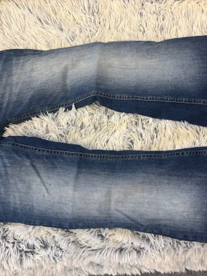 Blå slitna jeans i modellen blaze - Ett par klassiska blå jeans med raka ben och snyggt slitna detaljer på bakfickorna. Jeansen har en tvättad look med ljusare partier och normal midja. Perfekta för en avslappnad och trendig stil.