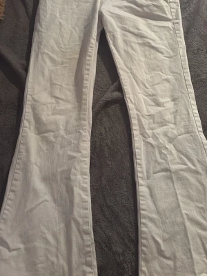 Vita vida jeans - Snygga vita jeans med utsvängda ben och klassisk passform. Byxorna har fickor bak och är tillverkade i ett lätt och luftigt linnematerial, perfekta för en avslappnad och trendig look.