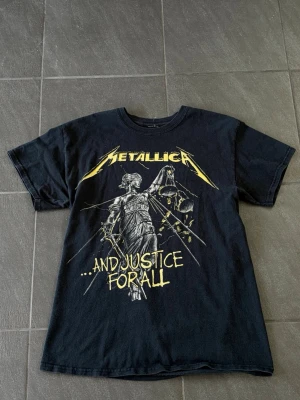 Metallica ”And Justice For All” t-shirt - Säljer en svart Metallica t-shirt med tryck från albumet '...And Justice For All' på både fram- och baksidan.  Modellen är 178 cm 70kg och passar Storleken bra. 