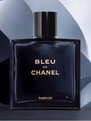 Bleu de Chanel Parfum - En elegant parfym från Chanel i en mörkblå, fyrkantig glasflaska med svart lock. Flaskan har guldtexten 'BLEU DE CHANEL PARFUM' på framsidan och utstrålar lyxig och modern känsla. Perfekt för dig som gillar exklusiva dofter.