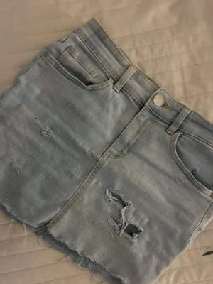 Ljusblå jeanskjol med slitningar -  säljaren ljusblå jeans kjol i storlek typ XS / S. Säljer den på grund av att jag vill bli av med alla sommarkläder.