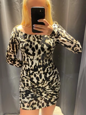 GUESS Leopardmönstrad långärmad klänning - En kort, figurnära klänning med leopardmönster i svart och beige från GUESS (nypris 3800kr)