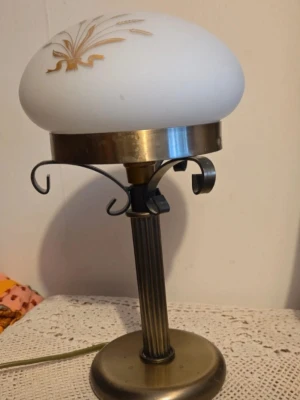 Bordslampa i mässing och glas - Säljer en vintage bordslampa med fot i mässingfärgad metall och dekorativt räfflat stativ. Skärmen är i vitt glas med guldfärgat blommönster. Lampan har en klassisk rund form och elsladd med stickkontakt.