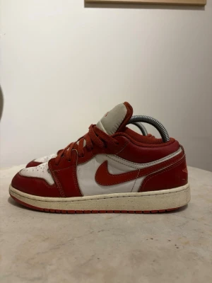 Nike Air Jordan 1 Low röd/vit - Säljer ett par Nike Air Jordan 1 Low sneakers i rött och vitt läder. Klassisk siluett med röd swoosh, vita paneler och röda detaljer på snörning och yttersula. Perfekta för dig som gillar streetwear och vill ha en ikonisk look.