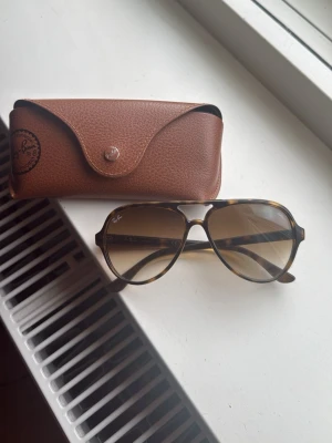 Ray-Ban Cats  - Snygga Ray-Ban Cats RB4125 solglasögon med brunmelerad båge och klassisk aviatorform. Glasen är tonade i brunt och bågen har Ray-Ban-logga på sidan. Kommer med originalbrunt fodral. Perfekt accessoar för soliga dagar. Väldigt bra skick.