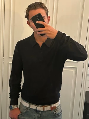 Stickad tröja Hollister - Säljer en svart stickad tröja från Hollister med halv dragkedja och krage. Tröjan har ett diskret rutmönster i stickningen och långa ärmar. Perfekt till jeans för en clean och stilren look.