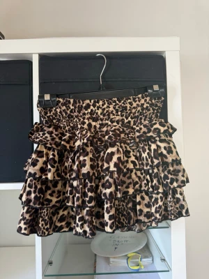 Leopardmönstrad volangkjol  - Supersnygg kjol med leopardmönster och flera lager volanger. Resår i midjan för skön passform och inbyggda shorts under kjolen. Använd en gång.