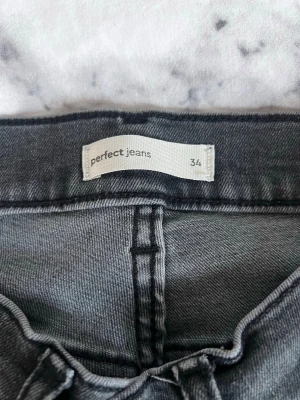 Svarta bootcut jeans från Perfect Jeans - Snygga svarta bootcut jeans från Perfect Jeans (gina tricot). Jeansen har klassisk femficksdesign och utsvängda ben. Materialet är mjukt denim i svart tvättad nyans som ger en cool look. Perfekta för dig som gillar retrostil och vill ha ett par jeans som sticker ut.