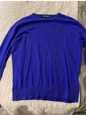 Ralph lauren stickat  - Kornblå långärmad tröja från Polo Golf Ralph Lauren med rund halsringning och diskret broderad logga på bröstet. Tillverkad i mjukt material som känns skönt mot huden. Perfekt för dig som gillar klassisk och stilren design.