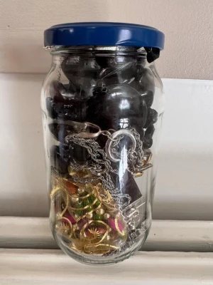 Blandade smycken i glasburk - Säljer en glasburk fylld med blandade smycken som halsband, ringar och armband i olika färger och material. Perfekt för dig som gillar att mixa och matcha accessoarer.