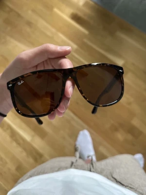 Bruna solglasögon från Ray-Ban - Snygga solglasögon från Ray-Ban med klassisk wayfarer-form och brunmelerad båge. Glasen är bruna och bågarna har en sköldpaddsmönstrad look som ger en tidlös vibe. Perfekta för soliga dagar och en stilren outfit.