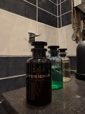 Ombre Nomade parfymflaska - Säljer en elegant parfymflaska med texten 'OMBRE NOMADE' i guld på svart glas. 100ml, cirka 75-80ml kvar. NYPRIS 4100kr 