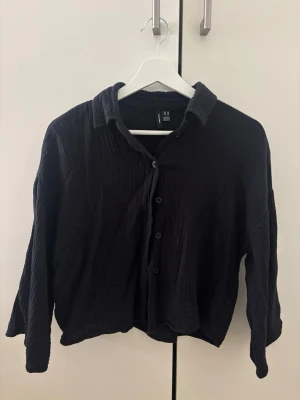 Svart oversized skjorta i bomull - Säljer en svart skjorta i mjukt, strukturerat bomullstyg. Skjortan har en avslappnad, oversized passform med långa ärmar och klassisk krage. Stängs med knappar framtill och passar perfekt till en chill vardagslook.