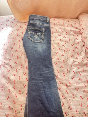 Blå bootcut jeans med slitningar - Blå bootcut jeans med slitningar. Jeansen har fem fickor och dekorativ brodyr på bakfickan. PRIS GÅR ATT DISKUTERAS💞