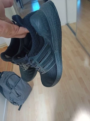 Svarta sneakers med stickad ovandel - Snygga helsvarta sneakers med stickad ovandel och robust sula. Skorna har en sportig look med plastdetaljer på sidorna och bekväm passform. Perfekta för dig som gillar stilrena och funktionella sneakers.