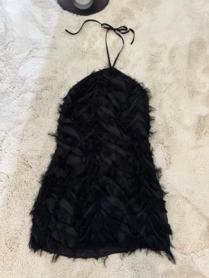  Halterneckklänning med öppen rygg NAKD - Säljer min svarta halterneckklänning med öppen rygg från Josefine HJ kollektion hos NAKD. Fjäderliknande detaljer. Tror jag köpte den för 600kr, säljer för 100kr. Storlek 36. Använd en gång. Passar perfekt till fest.🪻🌺