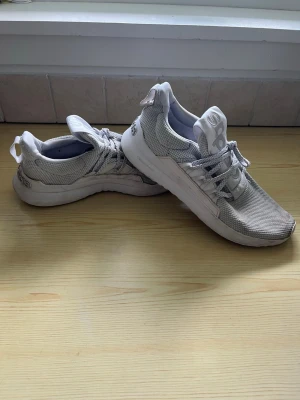 Vita mesh sneakers från Adidas strl 41 1/3 - Sneakers från Adidas i vitt meshmaterial med vita snören. Skorna har en sportig design med låg profil och bekväm sula. Storlek 41 1/3.