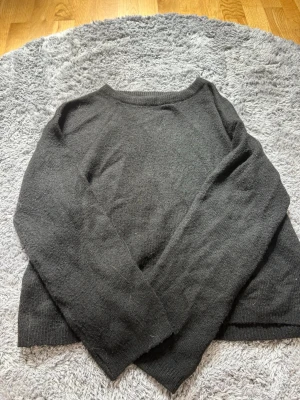 Mörkgrå stickad tröja från 157 - Mysig mörkgrå stickad tröja från 157 med rund halsringning och långa ärmar. Tröjan har en enkel och clean design som passar perfekt till jeans eller kjol. Materialet känns mjukt och bekvämt mot huden.
