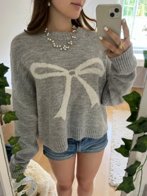Grå stickad tröja med rosett - Supersöt grå stickad tröja med rosett från Pull & Bear. Endast använd ett fåtal gånger💗
