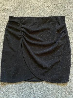 Glitterkjol - Svart, glittrig kjol från Kappahl i storlek M. Köpt på vinted men jag har aldrig använt den! Lite nopprig på baksidan, se sista bilden, men annars i gott skick 💕
