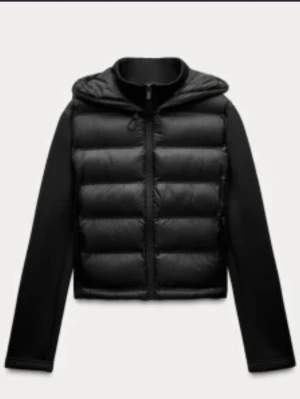 Svart pufferjacka med huva - Snygg svart pufferjacka med huva och dragkedja framtill. Jackan har quiltad, vadderad front och släta ärmar i kontrastmaterial. Perfekt för kalla vinterdagar och ger en modern look. Pris kan diskuteras men helst 250