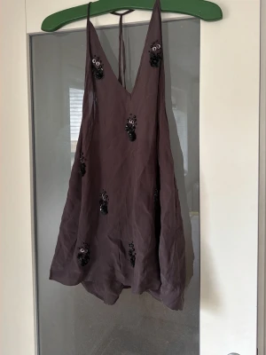 Massimo Dutti topp med paljettdetaljer - Helt ny och oanvänd Massimo Dutti-topp i ett vackert, tungt skirt tyg som faller fantastiskt. Djup V-ringning och eleganta paljett- och pärldetaljer som ger en exklusiv känsla. Perfekt till fest, middag eller när du vill klä upp en enkel outfit. Helt ny • Exklusiv känsla • Snyggt fall