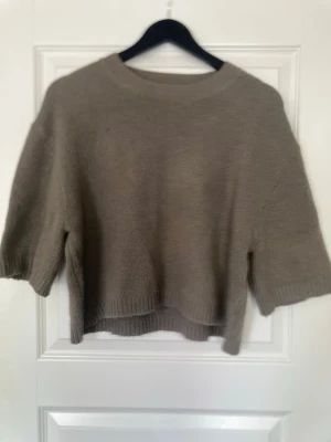 Beige stickad tröja från Amisu - Beige stickad tröja från Amisu med avslappnad passform och halvlånga ärmar. Tröjan har rund halsringning och ribbade muddar vid ärmslut och nederkant. Perfekt för lager-på-lager och enkel att matcha med jeans eller kjol.