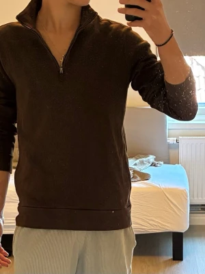 Brun halvzip tröja från Polo Ralph Lauren - Säljer en brun långärmad tröja från Polo Ralph Lauren med halvzip och klassisk krage. Tröjan har diskret broderad logga på bröstet och är tillverkad i ett mjukt bomullsmaterial. Perfekt för en stilren och avslappnad look.