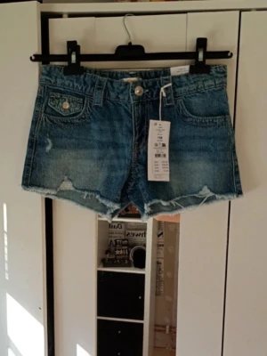 Blå jeansshorts  - Snygga blå jeansshorts från gina Tricot med råa kanter och slitna detaljer. Klassisk femficksmodell med knapp och dragkedja framtill samt fickor med lock bak. Perfekta för varma dagar och enkel att matcha med allt ☀️💗