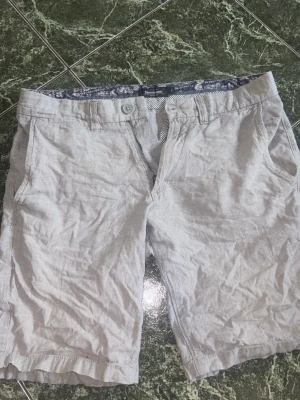 Grå kortbyxor - Säljer ett par ljusgråa kortbyxor med snyggt mönster i byxan i färg mörkblå/lila. Storlek S. Märket är dressman. Skicket är rätt bra, lite skrynkliga bara. Hör av dig vid minsta lilla fråga eller bild!