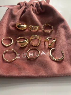 9-pack guldfärgade ringar - Säljer ett set med 9 olika guldfärgade ringar i varierande former och design. Ringarna har både släta och tvistade detaljer, vissa med öppna ändar och andra med mer organiska former. Perfekt för att mixa och matcha för en personlig stil.
