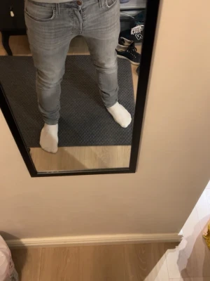 Ljusgrå slim fit jeans herr - Säljer ett par ljusgrå slim fit jeans med klassisk femficksdesign och dragkedjegylf. Jeansen har en snygg tvättad look och raka ben. Perfekta för dig som gillar en modern och enkel stil.