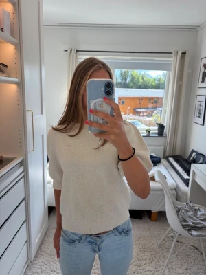 beige stickad tröja med kort ärm - En beige stickad tröja från Vero Moda med korta, puffiga ärmar och ribbad vid hals och nederkant. Tröjan har ett hål på framsida (se på bilden ovan), men är överlag en väldigt fin tröja 💕💕