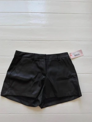 Svarta skinn shorts från Nelly - Snygga svarta shorts i PU-material från Nelly. Aldrig andvända och har lappen kvar