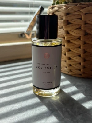 Coconilla Eau de Parfum 50 ml - Coconilla Eau de Parfum kommer i en stilren, genomskinlig glasflaska med svart lock och vit etikett. Doften har en ljusgul vätska och flaskan rymmer 50 ml. Perfekt för dig som gillar fräscha och söta dofter.