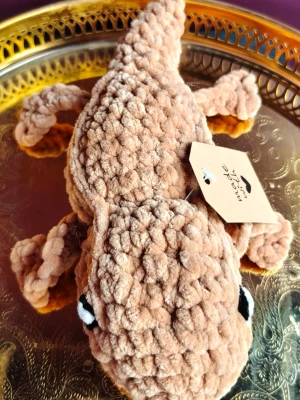 Beige virkad ödla i mjukt garn - Unik handgjord ödla i beige, fluffigt garn med stora svarta och vita ögon. Virkad i ett tjockt, mjukt material som gör den gosig och dekorativ. Perfekt som prydnad eller mysig maskot till rummet.