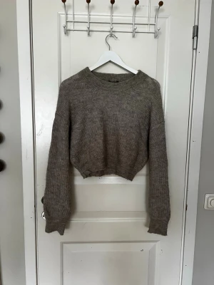 Beige stickad tröja från Lindex - Mysig beige stickad tröja från Lindex i storlek XS. Tröjan har en croppad passform, ribbstickade muddar och rund halsringning. Perfekt för lager på lager och enkel att matcha med jeans eller kjol.