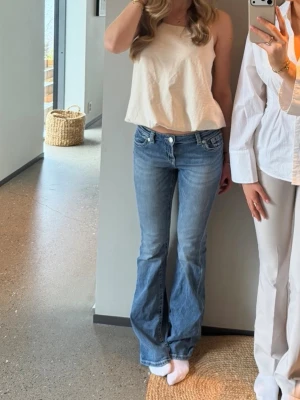 Blå bootcut jeans med mönster på fickorna  - Blåa bootcut jeans med mönster på fickorna 