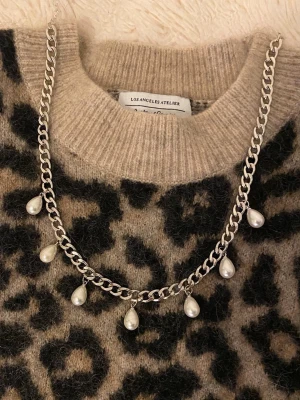 Silverfärgat halsband med pärldroppar - Säljer ett snyggt halsband i silverfärgad rostfritt med sju droppformade pärlor som hänger längs kedjan. Perfekt för dig som vill ha en trendig accessoar med lite extra edge. Kedjan är chunky och ger ett coolt intryck, medan pärlorna tillför en elegant touch.