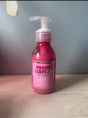 PROFFS Leave-In med arganolja - PROFFS Leave-In är en rosa hårvårdsprodukt med arganolja i en plastflaska med pump. Den är vegansk och har en återfuktande formula som ger näring och glans till håret. Perfekt för dig som vill ha mjukt och fräscht hår utan att skölja ur produkten.