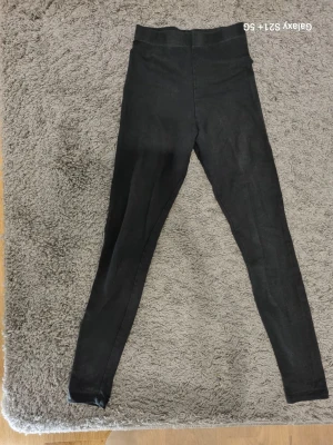 Svarta leggings från H&M Basic XS - Ett par klassiska svarta leggings från H&M Basic i storlek XS. De har hög midja och är tillverkade i ett stretchigt material som sitter skönt mot kroppen. Perfekta att matcha med oversized tröjor eller hoodies för en chill look.