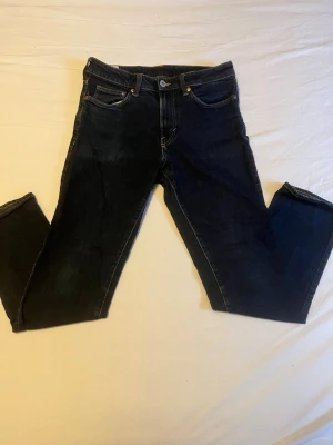 Mörkblå regular fit jeans - Säljer ett par mörkblå jeans i regular fit med klassisk femficksmodell och raka ben. Jeansen är tillverkade i denim och har snygga kontrastsömmar. Perfekta för en avslappnad och stilren look.