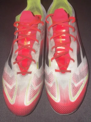 Adidas F50 fotbollsskor röd/vit - Säljer ett par Adidas F50 fotbollsskor i rött, vitt och neongult. Skorna har en låg profil, snörning och mönstrad ovandel i syntetmaterial. Klassiska svarta Adidas-ränder på sidorna och F50-tryck. Perfekta för snabba spelare på planen. Klippt skonörerna i toppen då dem gick sönder lite 