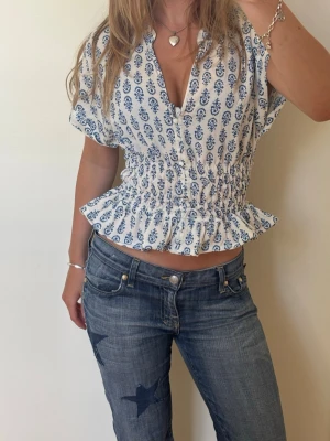 Viral H&M blus med blått mönster och volang - Säljer denna supersöta virala blusen från H&M i storlek s. Superfin nu till sommaren. Har knappar längst fram, lite längre ärmar och påsydd smock i midjan så den är figursydd. Ställ gärna frågor och kika gärna på mina andra annonser! 🩷🌸  Viral  Blus Figursydd