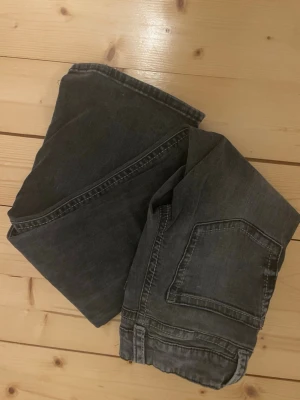 Lågmidjade bootcut jeans - Säljer ett par mörkgrå bootcut jeans med låg midja och dubbla knappar fram. De är använda ganska mycket men är ändå i jätte bra skick (inga slitningar vid hälarna osv) säljer då de håller på att bli för små 💕