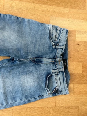 Ljusblå raka jeans från Replay - Snygga ljusblå jeans från Replay med raka ben och klassisk femficksmodell. Jeansen har slitna detaljer och en patch med Replay-logga bak i midjan. Perfekta för en avslappnad och trendig look.